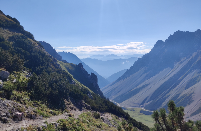 Descending from the Anhalter Hütte after a night in the mountains on the Adlerweg in the Austrian Tirol. Early morning sun lights the mountains beneath a blue sky