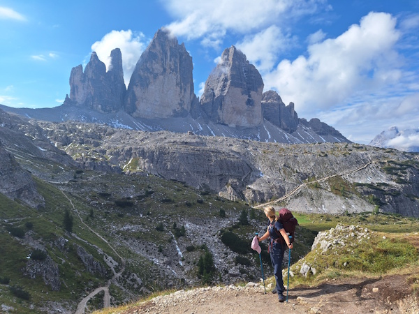 A hiker looks at the Tre Cime rock formation in the Dolomites