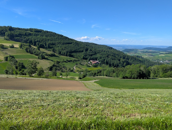 View across fields to a farm on Stage 2 of the Swiss Jura Crest Trail 