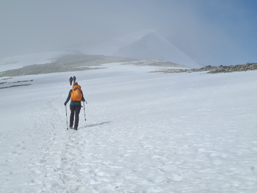 walkers head into the cloud on snow covered Glittertind