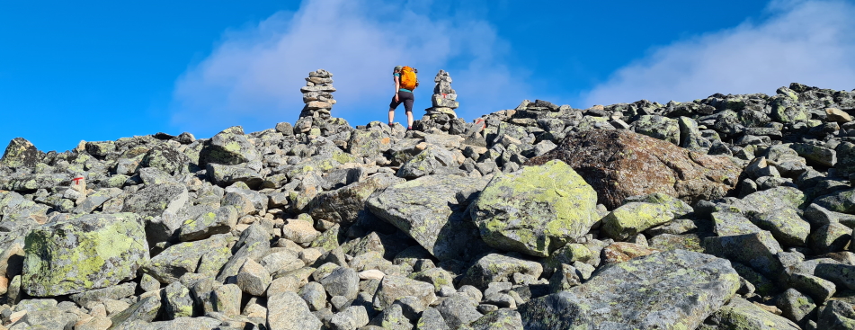 a hiker climbs uphill on a rocky boulderfield