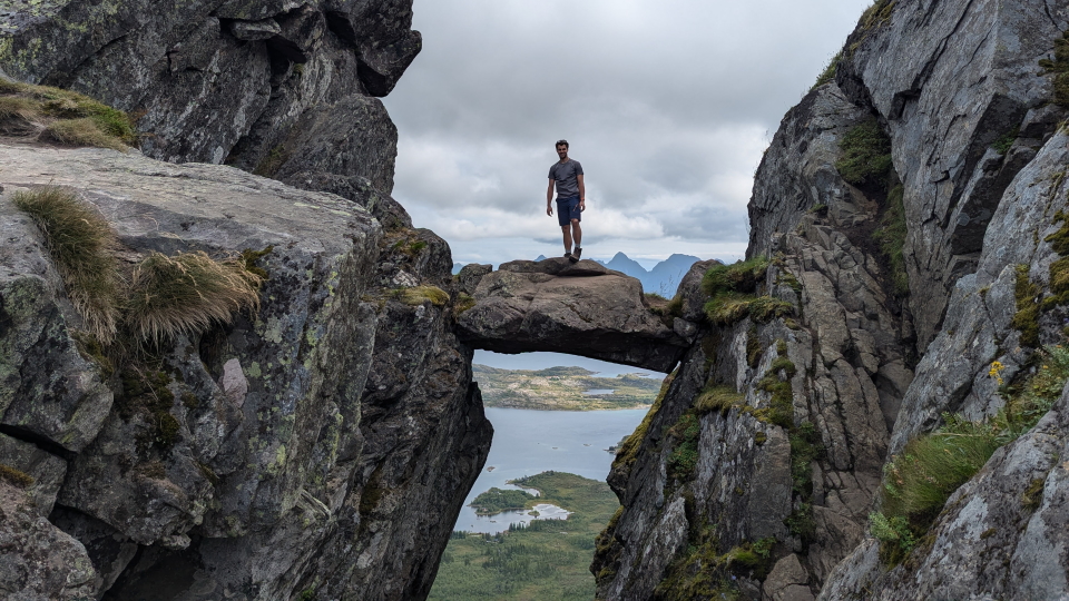 The famous floating rock of the Djevelporten (Devil's Gate), Lofoten, with a hiker on top