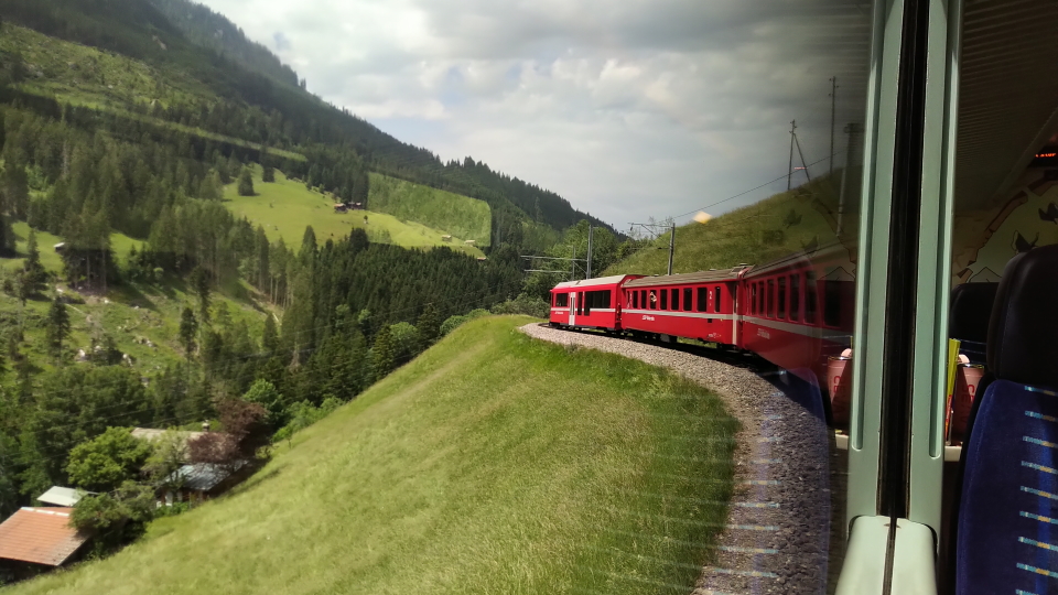 The red Swiss train descends in curves from the mountain resort of Arosa